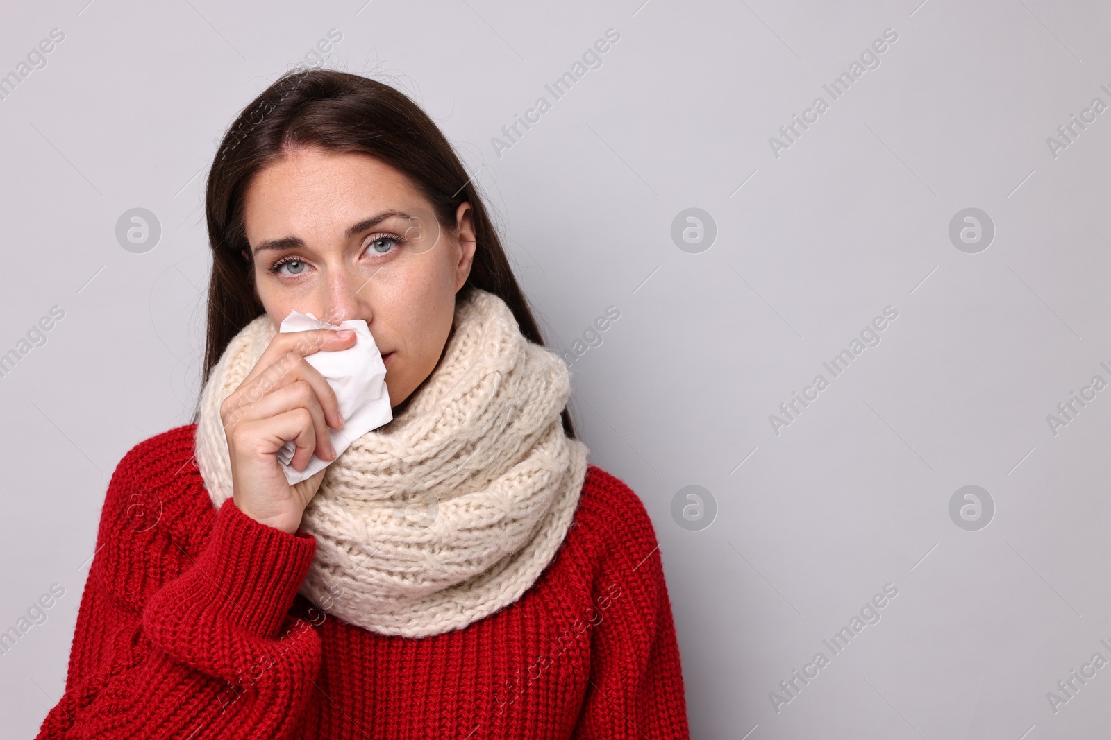 Photo of Sick woman with tissue on grey background, space for text. Cold symptoms