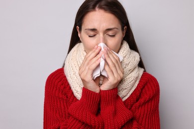 Photo of Sick woman with tissue on grey background. Cold symptoms