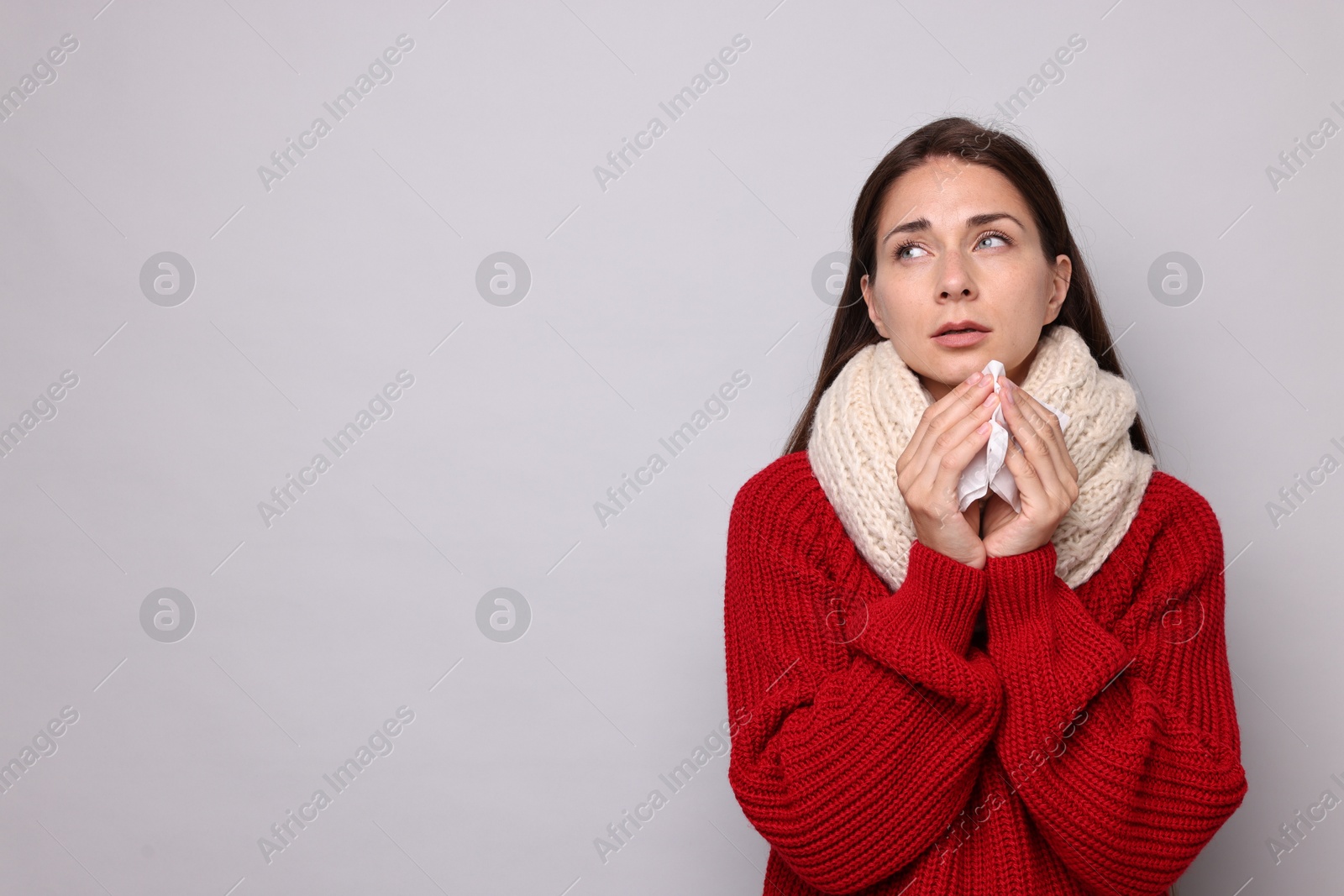 Photo of Sick woman with tissue on grey background, space for text. Cold symptoms