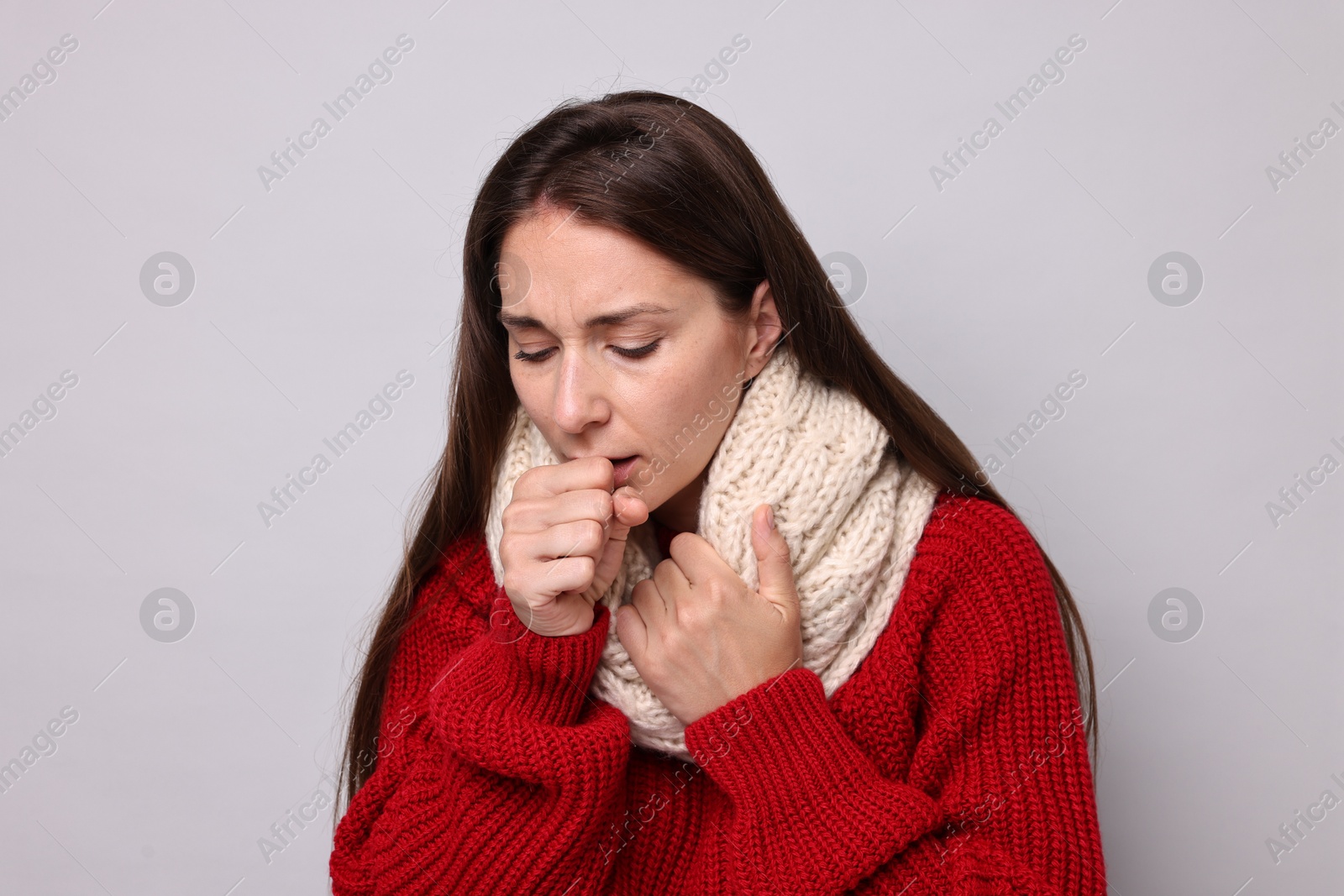 Photo of Sick woman coughing on grey background. Cold symptoms