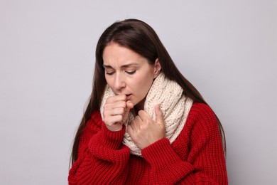 Photo of Sick woman coughing on grey background. Cold symptoms
