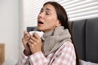 Photo of Sick woman with tissue sneezing in bed. Cold symptoms