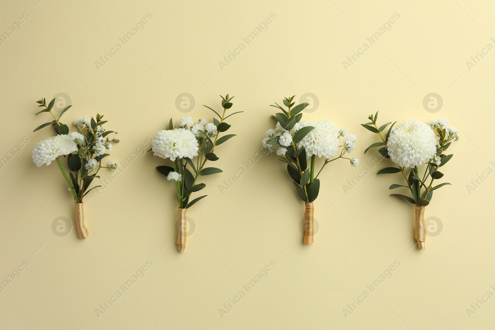 Photo of Many stylish boutonnieres on beige background, flat lay