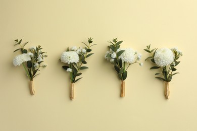 Many stylish boutonnieres on beige background, flat lay