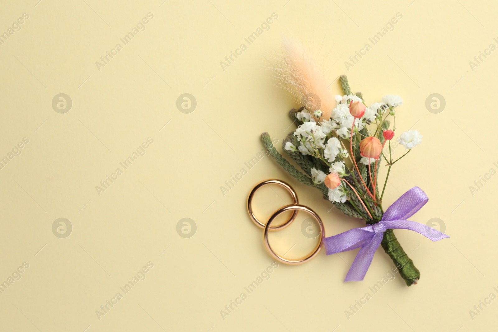 Photo of Small stylish boutonniere and rings on beige background, flat lay. Space for text