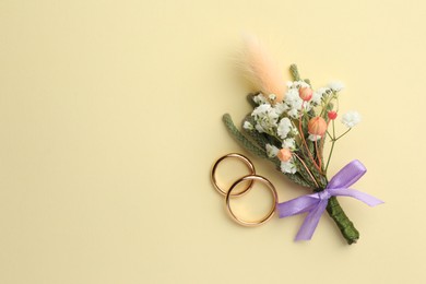 Small stylish boutonniere and rings on beige background, flat lay. Space for text