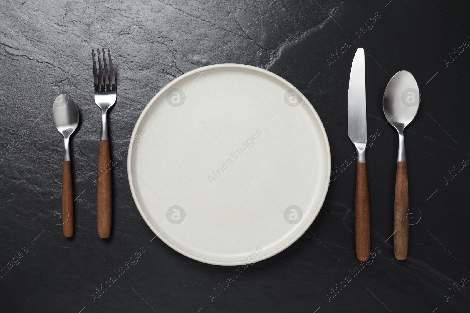 Photo of Stylish cutlery and plate on black table, flat lay