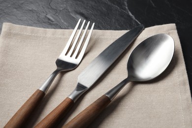 Photo of Stylish cutlery and napkin on black table