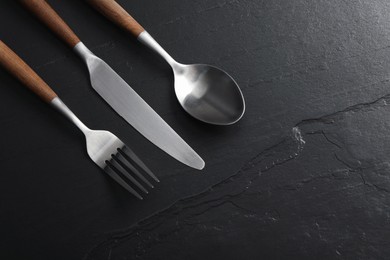 Photo of Stylish cutlery on black table, flat lay. Space for text