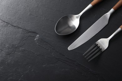 Stylish cutlery on black table, flat lay. Space for text