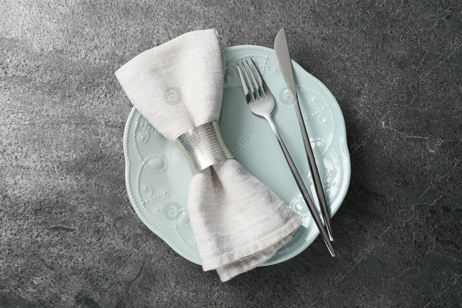 Photo of Stylish silver cutlery, plate and napkin on grey table, top view