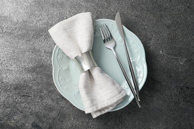 Photo of Stylish silver cutlery, plate and napkin on grey table, top view