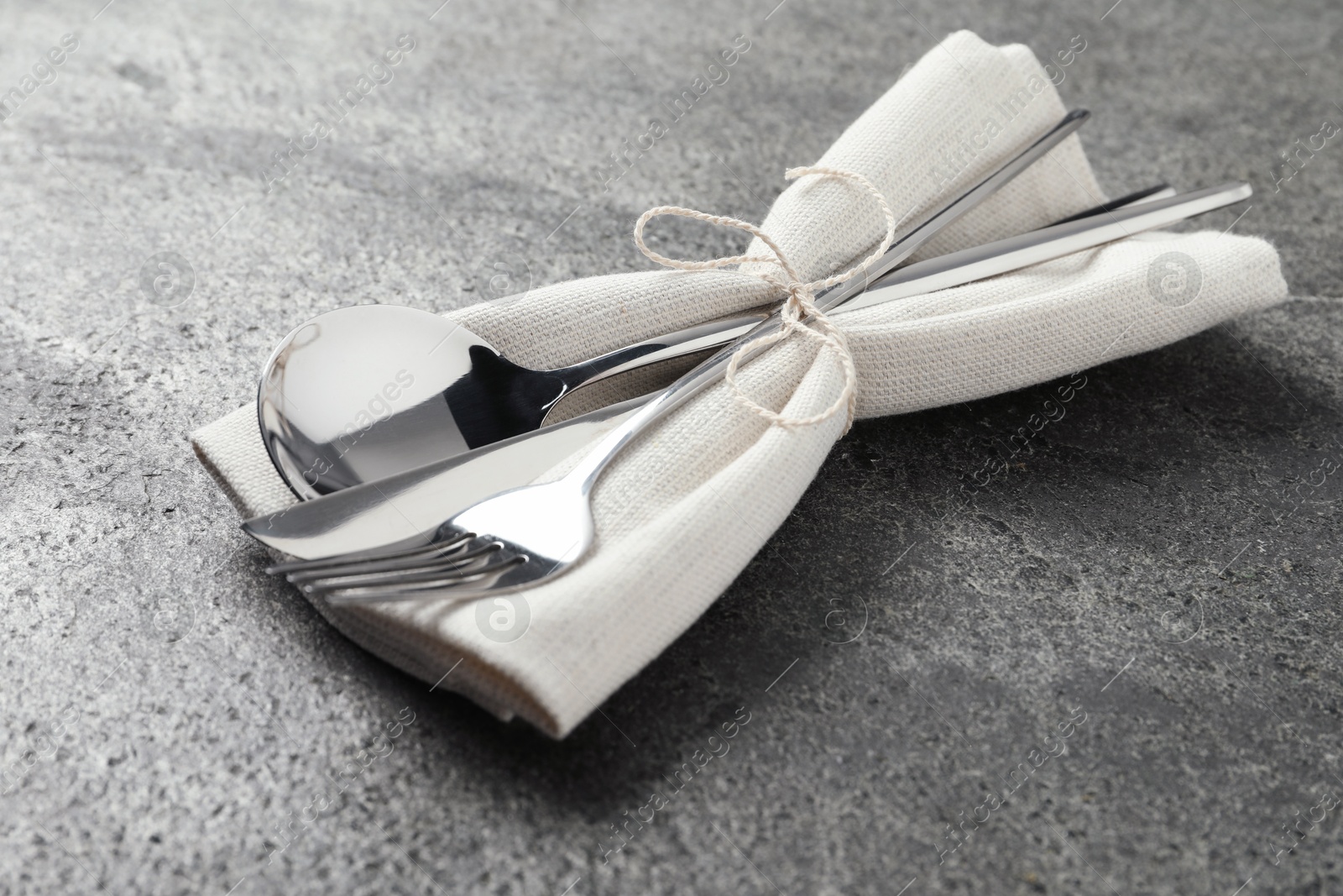 Photo of Stylish silver cutlery and napkin on grey table