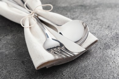 Photo of Stylish silver cutlery and napkin on grey table, closeup