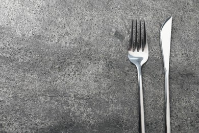 Photo of Stylish silver cutlery on grey table, top view. Space for text