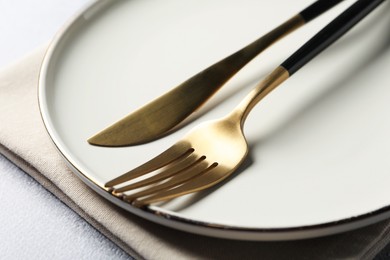 Photo of Stylish golden cutlery, plate and napkin on grey table, closeup