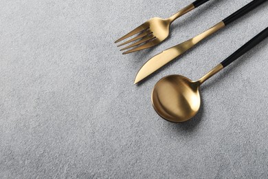 Photo of Stylish golden cutlery on grey table, above view. Space for text