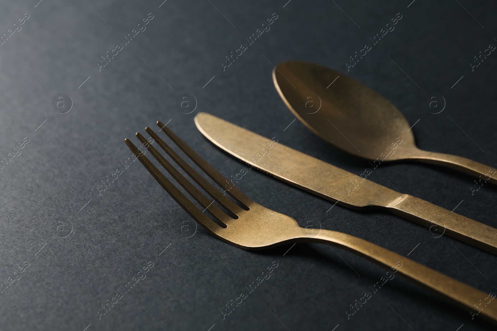 Photo of Elegant golden cutlery on black background, closeup