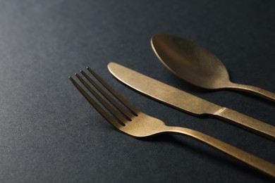 Photo of Elegant golden cutlery on black background, closeup