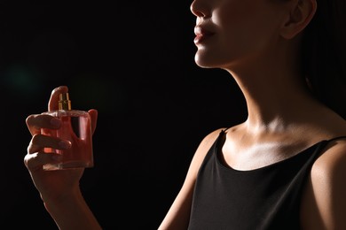 Photo of Woman with perfume on black background, closeup