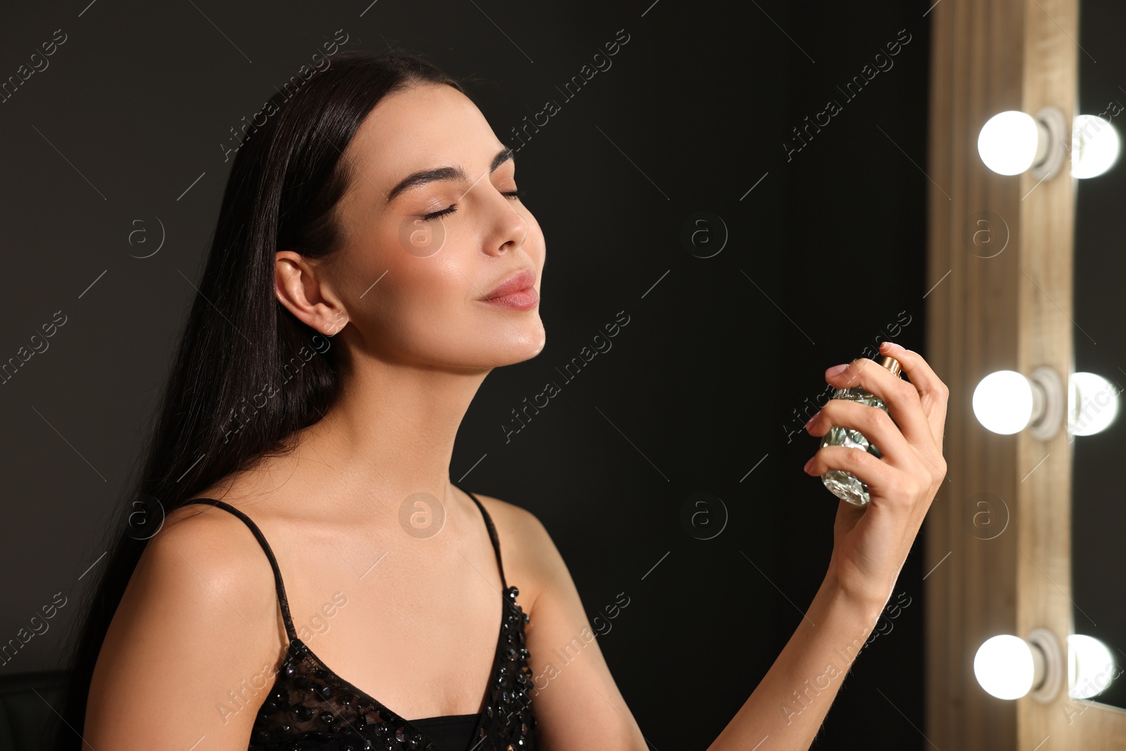 Photo of Beautiful woman spraying perfume in makeup room