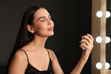 Photo of Beautiful woman spraying perfume in makeup room