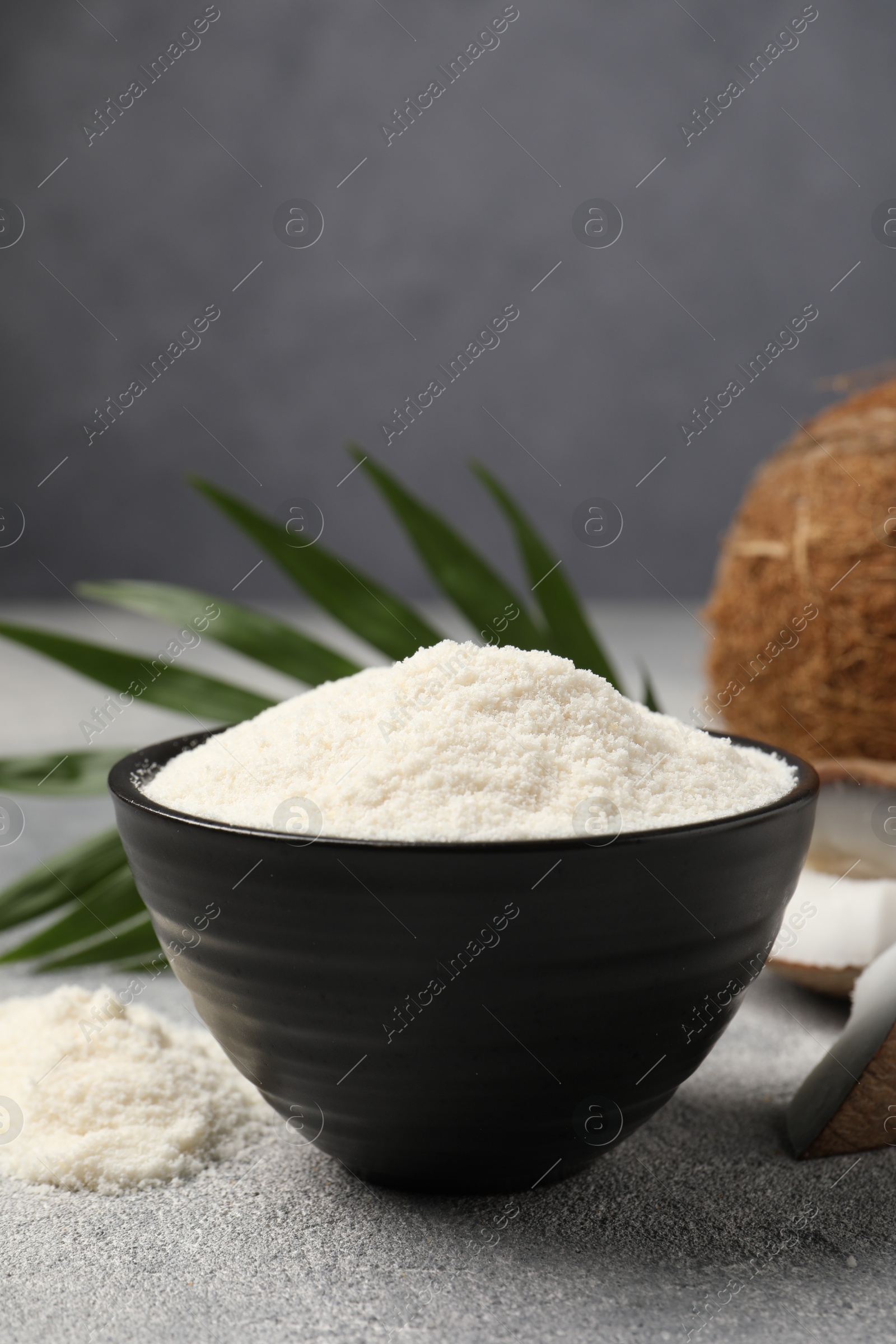 Photo of Coconut flour in bowl on light grey table, closeup