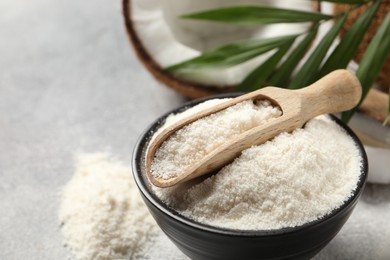 Photo of Coconut flour in bowl and scoop on light grey table, closeup