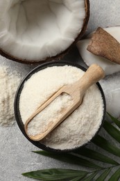 Photo of Coconut flour in bowl, scoop, fresh fruits and leaf on light grey table, flat lay