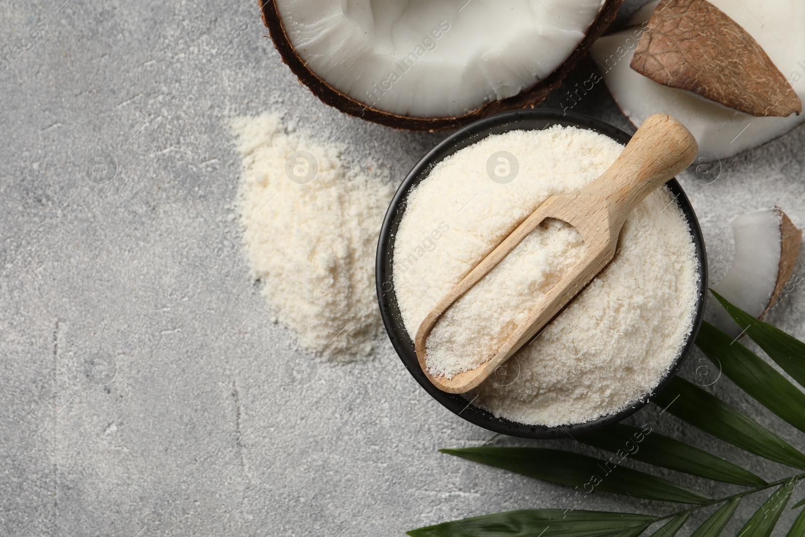 Photo of Coconut flour in bowl, scoop, fresh fruits and leaf on light grey table, flat lay. Space for text