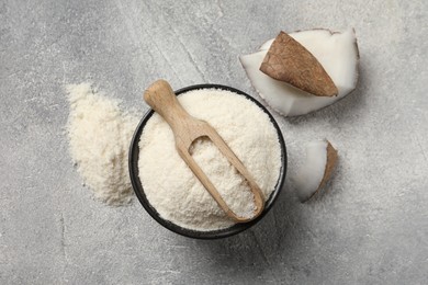 Photo of Coconut flour in bowl, scoop and fruit pieces on light grey table, flat lay