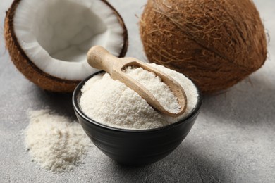 Photo of Coconut flour in bowl, scoop and fresh fruits on light grey table, closeup