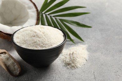 Photo of Coconut flour in bowl, scoop, fresh fruit and leaf on light grey table. Space for text