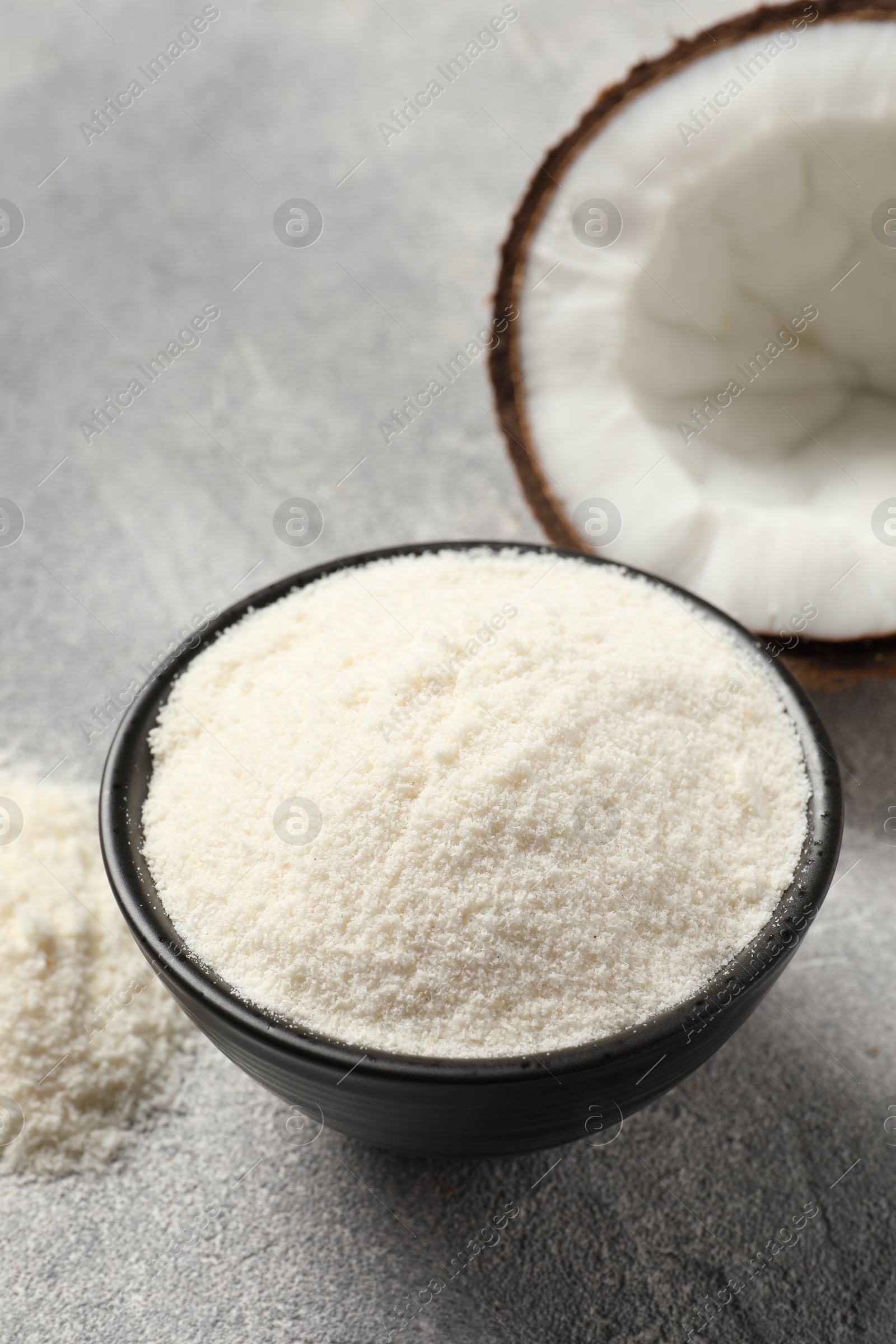 Photo of Coconut flour in bowl and fresh fruit on light grey table, closeup