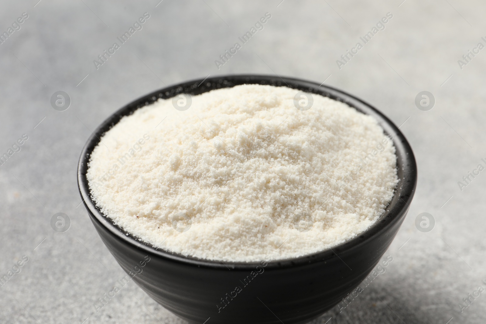 Photo of Coconut flour in bowl on light grey table, closeup