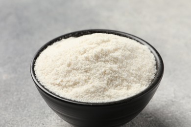 Photo of Coconut flour in bowl on light grey table, closeup