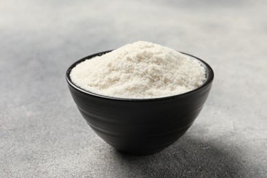 Photo of Coconut flour in bowl on light grey table, closeup