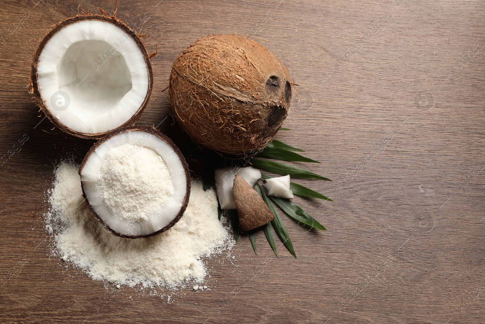 Photo of Coconut flour, fresh fruits and leaf on wooden table, flat lay. Space for text