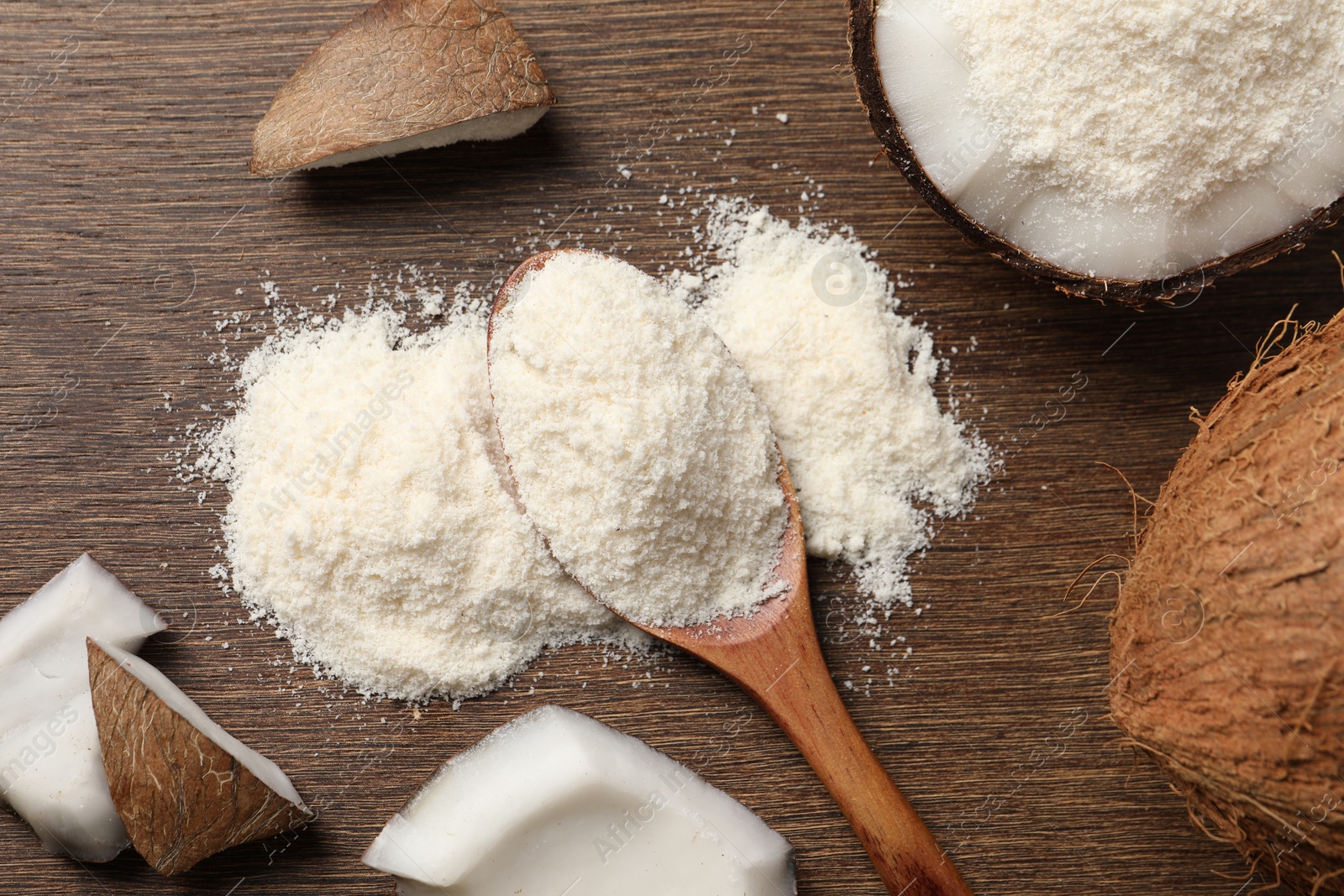 Photo of Coconut flour in spoon and fresh fruits on wooden table, flat lay