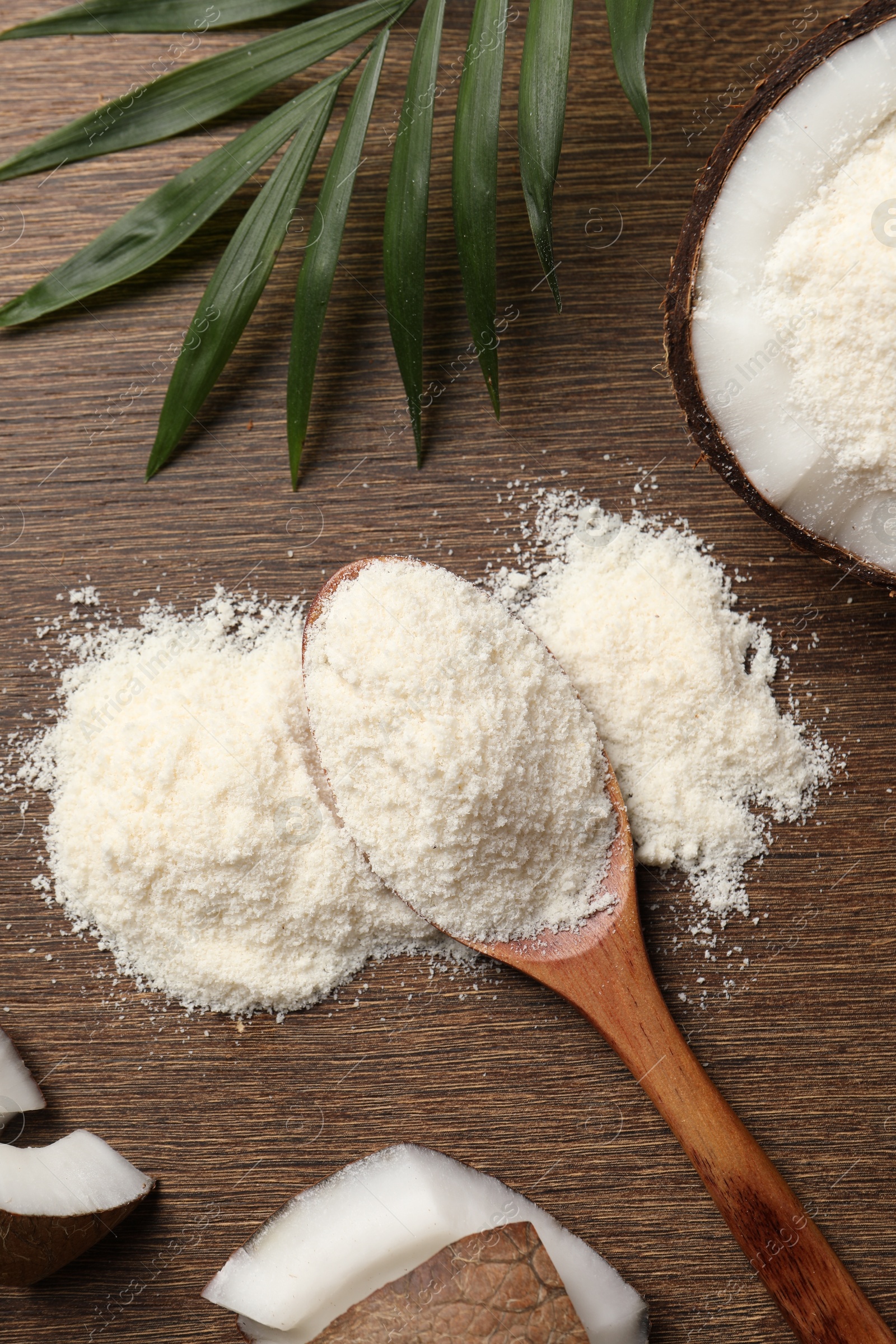 Photo of Coconut flour in spoon, fresh fruits and leaf on wooden table, flat lay