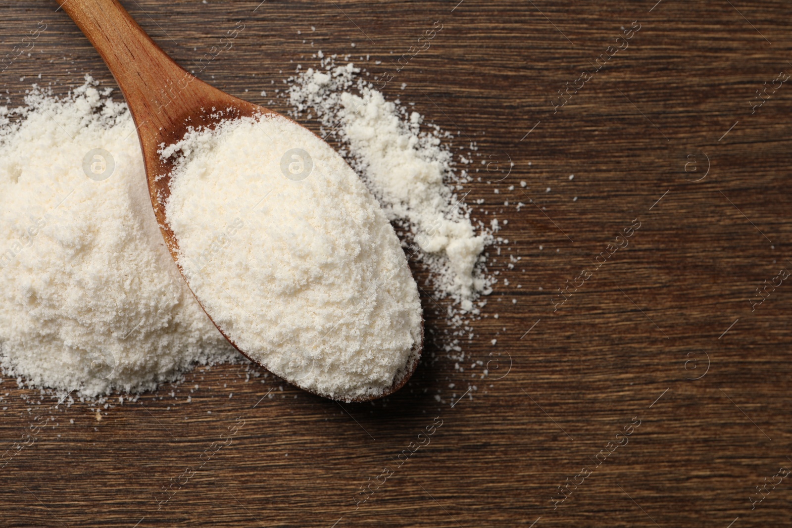 Photo of Coconut flour in spoon on wooden table, top view. Space for text