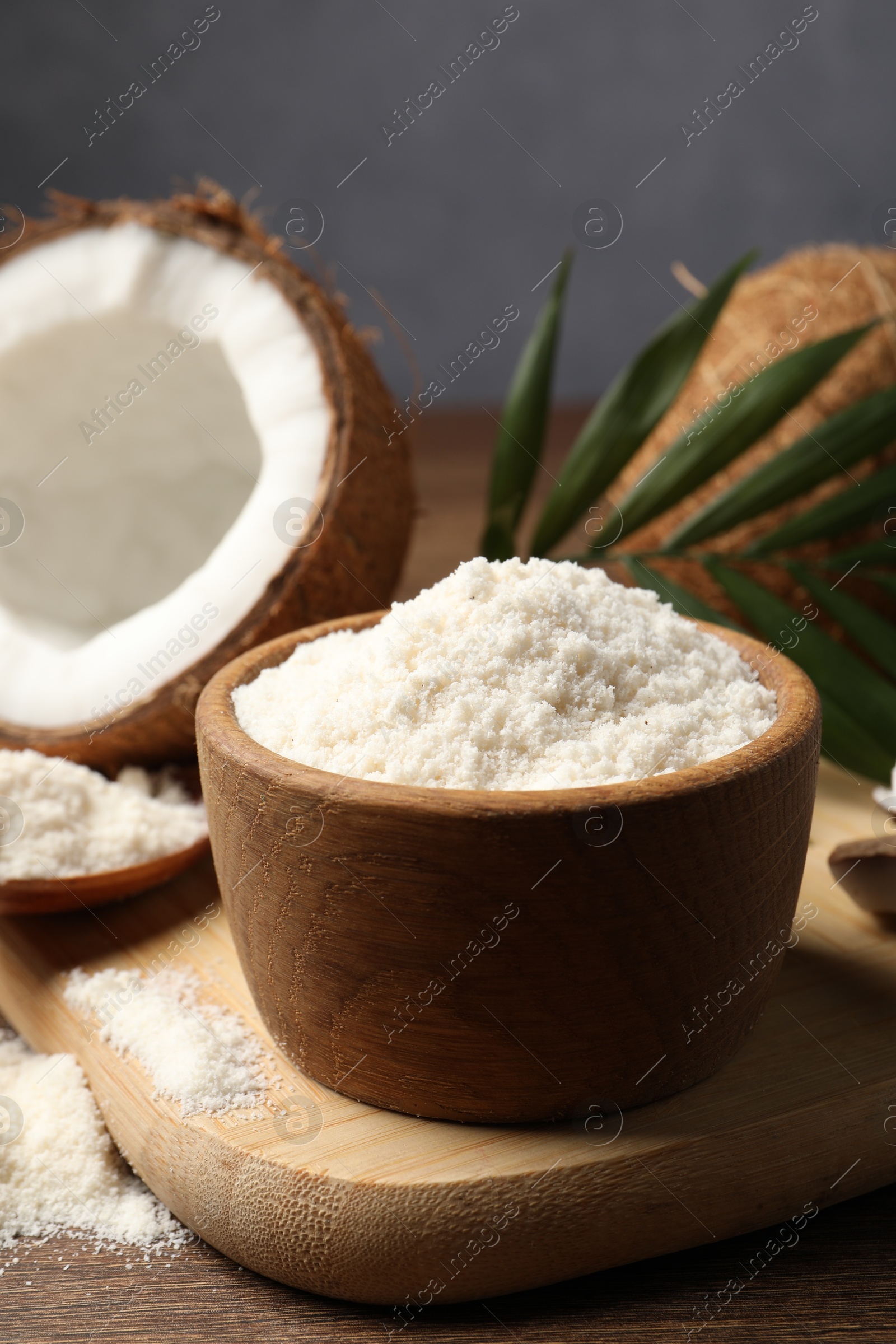 Photo of Coconut flour in bowl and fresh fruits on wooden table