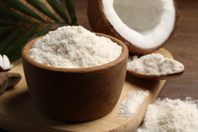 Photo of Coconut flour in bowl, spoon and fresh fruit on wooden table, closeup