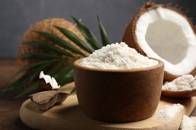 Photo of Coconut flour in bowl and fresh fruits on wooden table, closeup