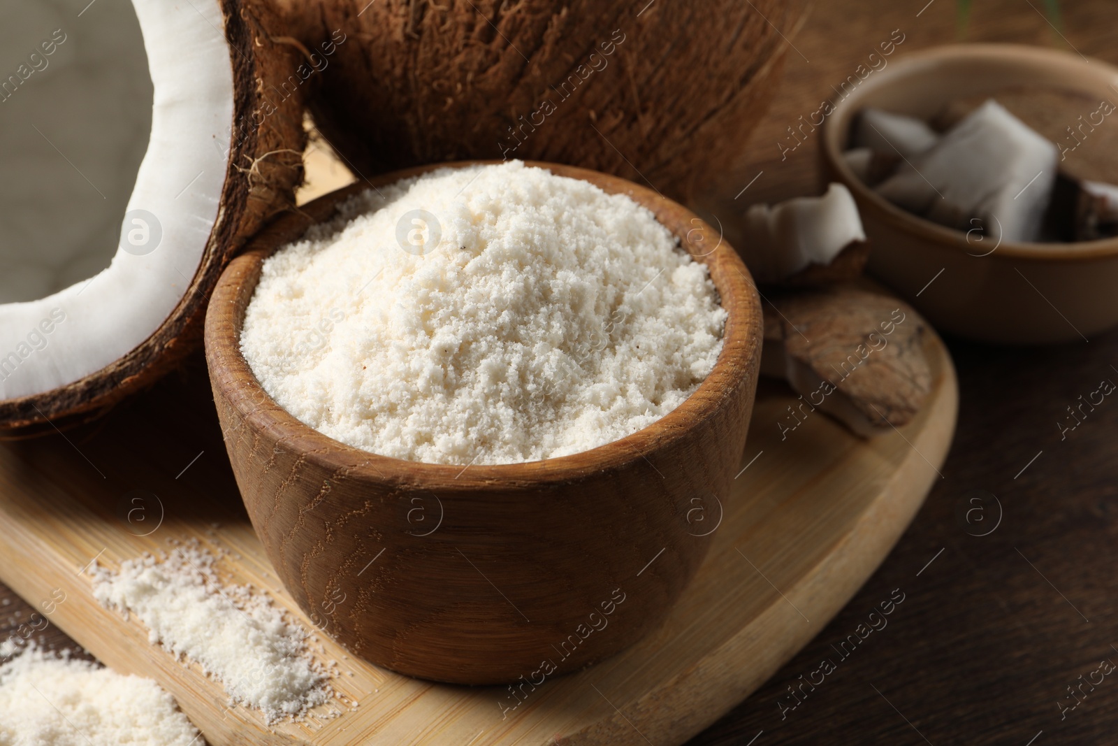 Photo of Coconut flour in bowl and fresh fruits on wooden table, closeup