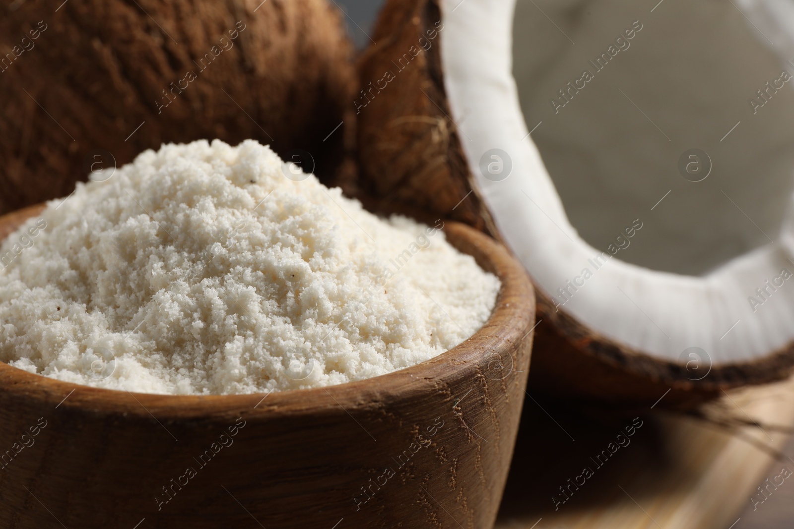 Photo of Coconut flour in bowl and fresh fruits on table, closeup