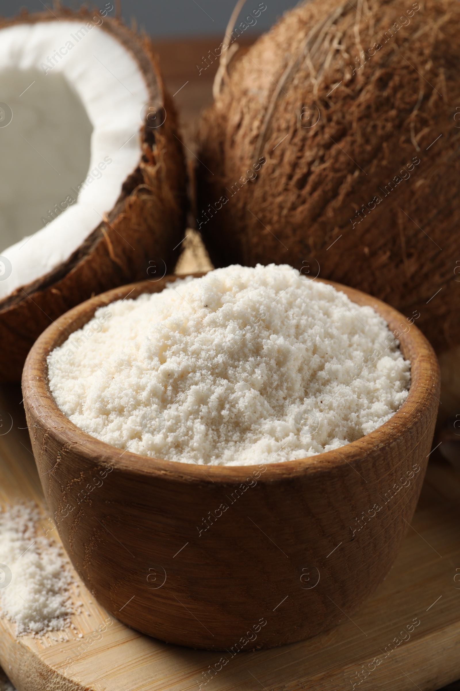 Photo of Coconut flour in bowl and fresh fruits on table, closeup