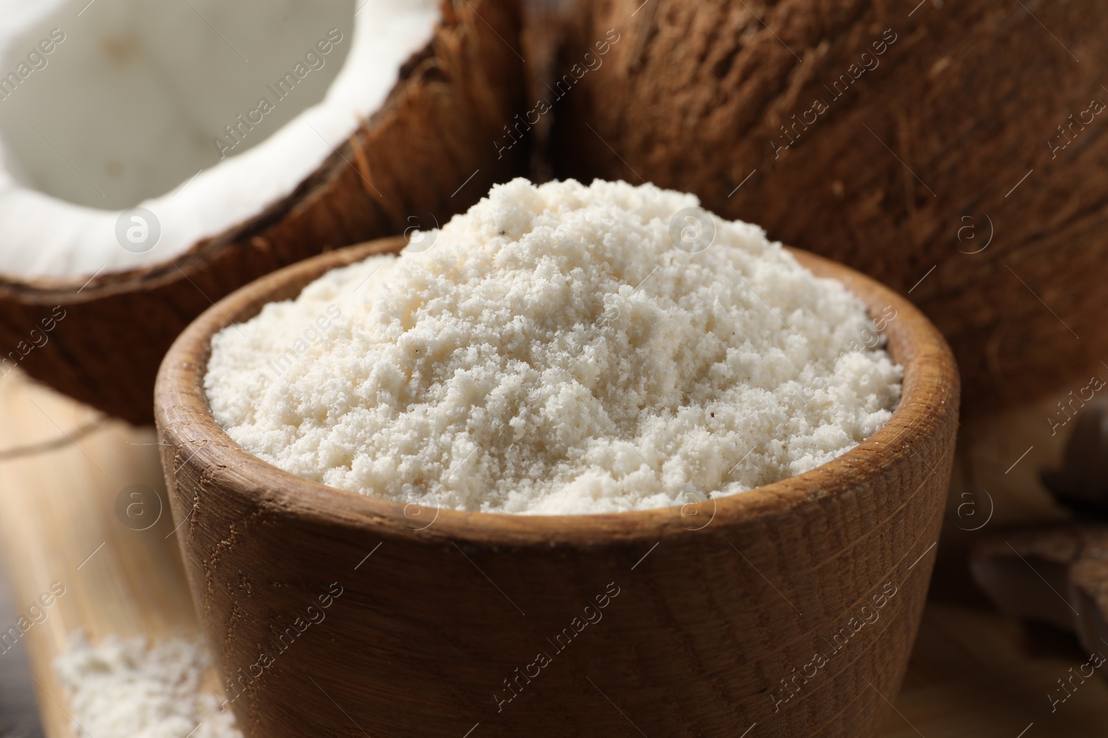 Photo of Coconut flour in bowl and fresh fruits on table, closeup