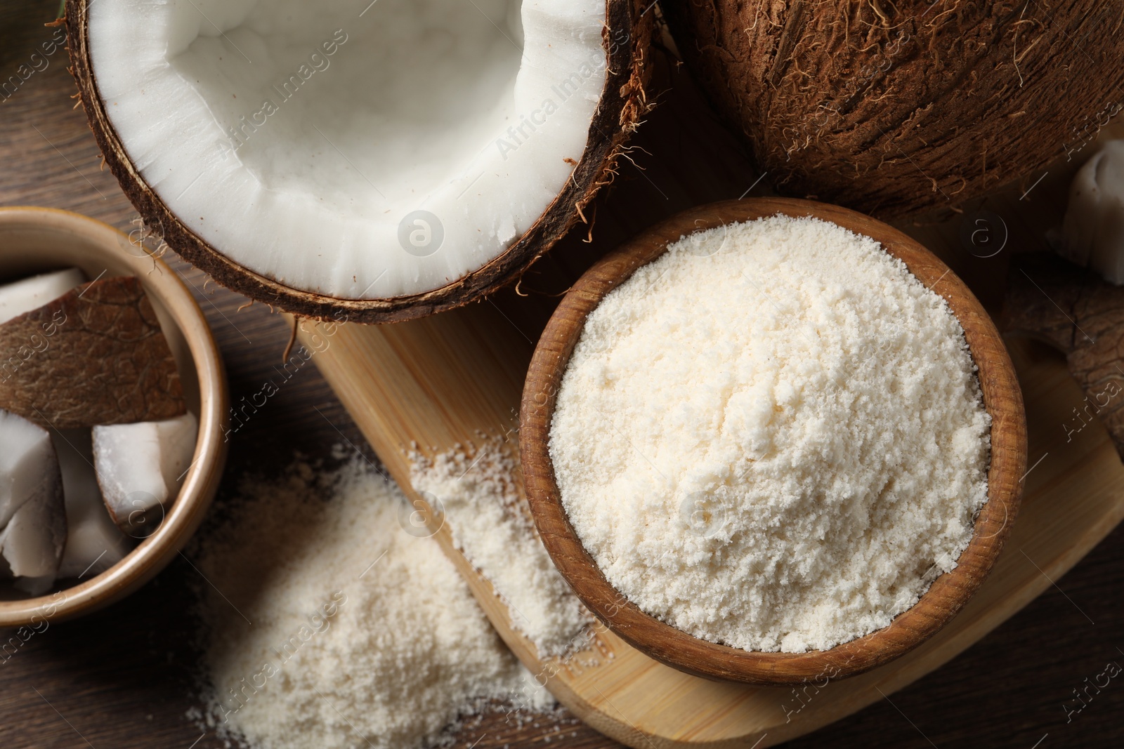 Photo of Coconut flour in bowl and fresh fruits on wooden table, flat lay