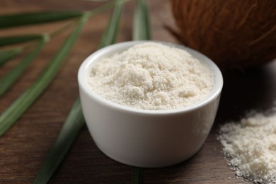 Photo of Organic coconut flour in bowl on wooden table, closeup